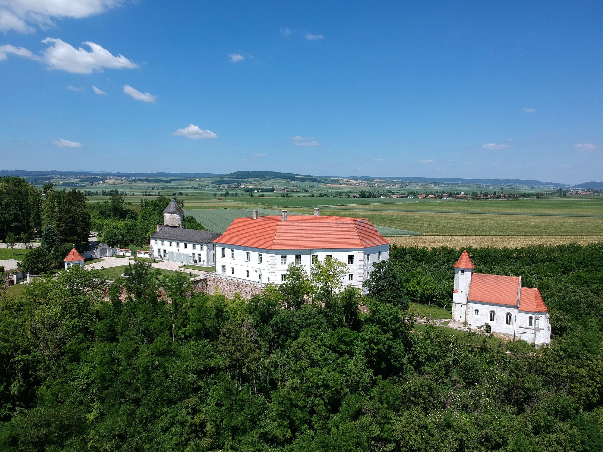 Letecký pohľad na hrad Viehofen s červenou strechou, obklopený zelenou krajinou a poľami.