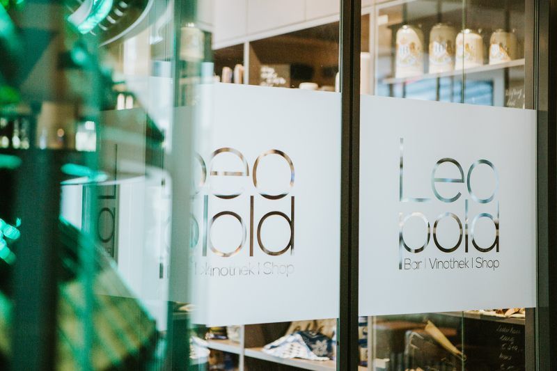 Vchod do vinotéky s nápisom "Leopold Bar Vinothek Shop" na sklenených dverách.