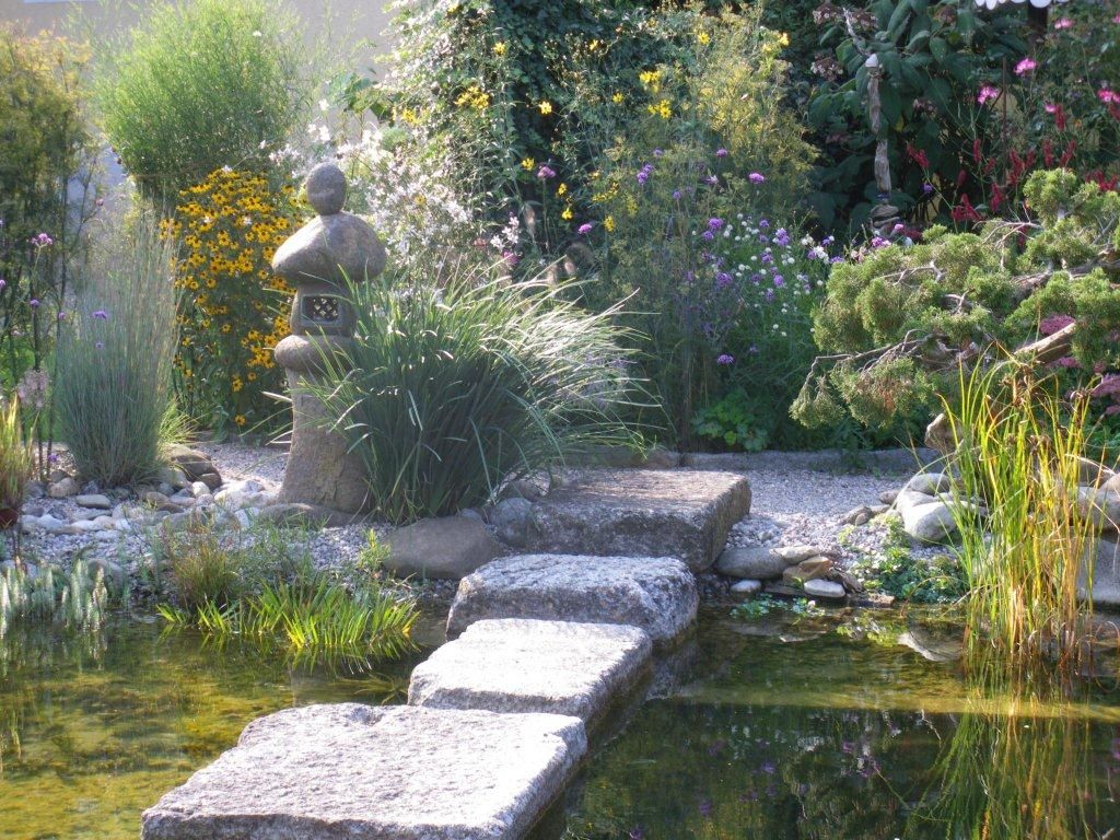 Výstavná záhrada s kamennou lucernou, kvetmi a jazierkom.