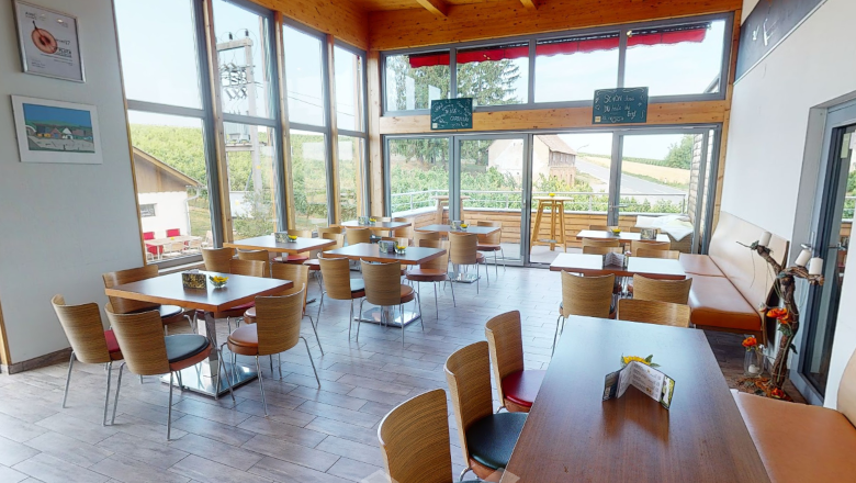 Pohľad do interiéru modernej Viechy s dreveným nábytkom a veľkými oknami.