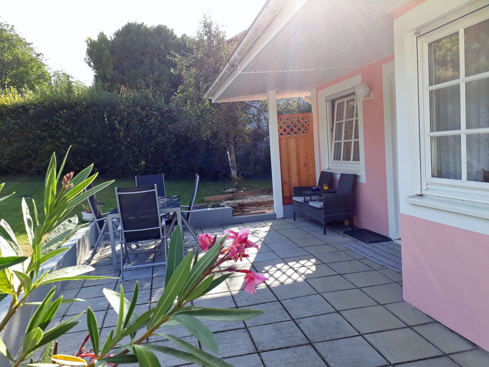 Terasa so záhradným nábytkom a ružovou fasádou domu.