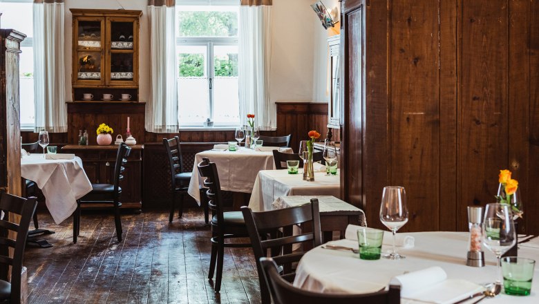 Útulná krčma s dreveným nábytkom a prestretými stolmi.