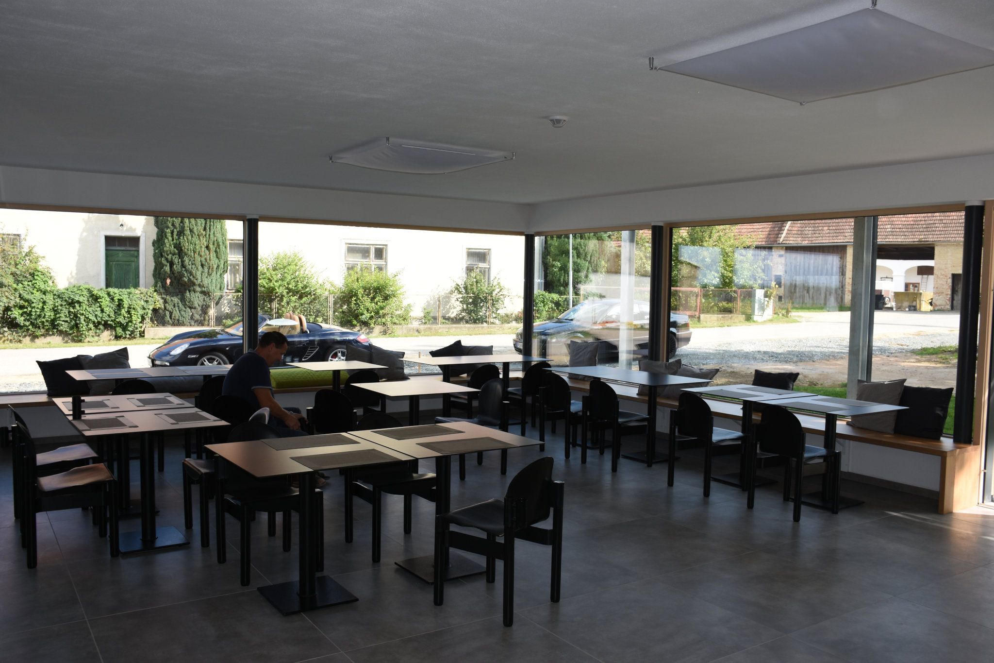 Großer Frühstücksraum mit komplett verglaster Wand und vielen Sitzmöglichkeiten.