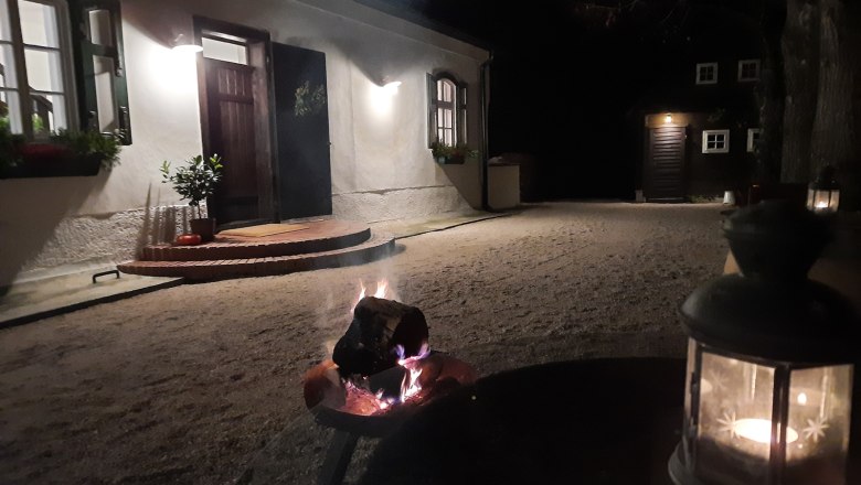 Osvetlen&eacute; n&aacute;dvorie v noci s ko&scaron;om na oheň a lamp&aacute;&scaron;om v popred&iacute;.