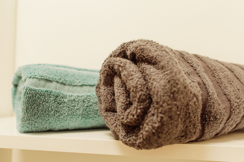 Na poličke ležia dva uteráky, jeden tyrkysový a druhý hnedý.