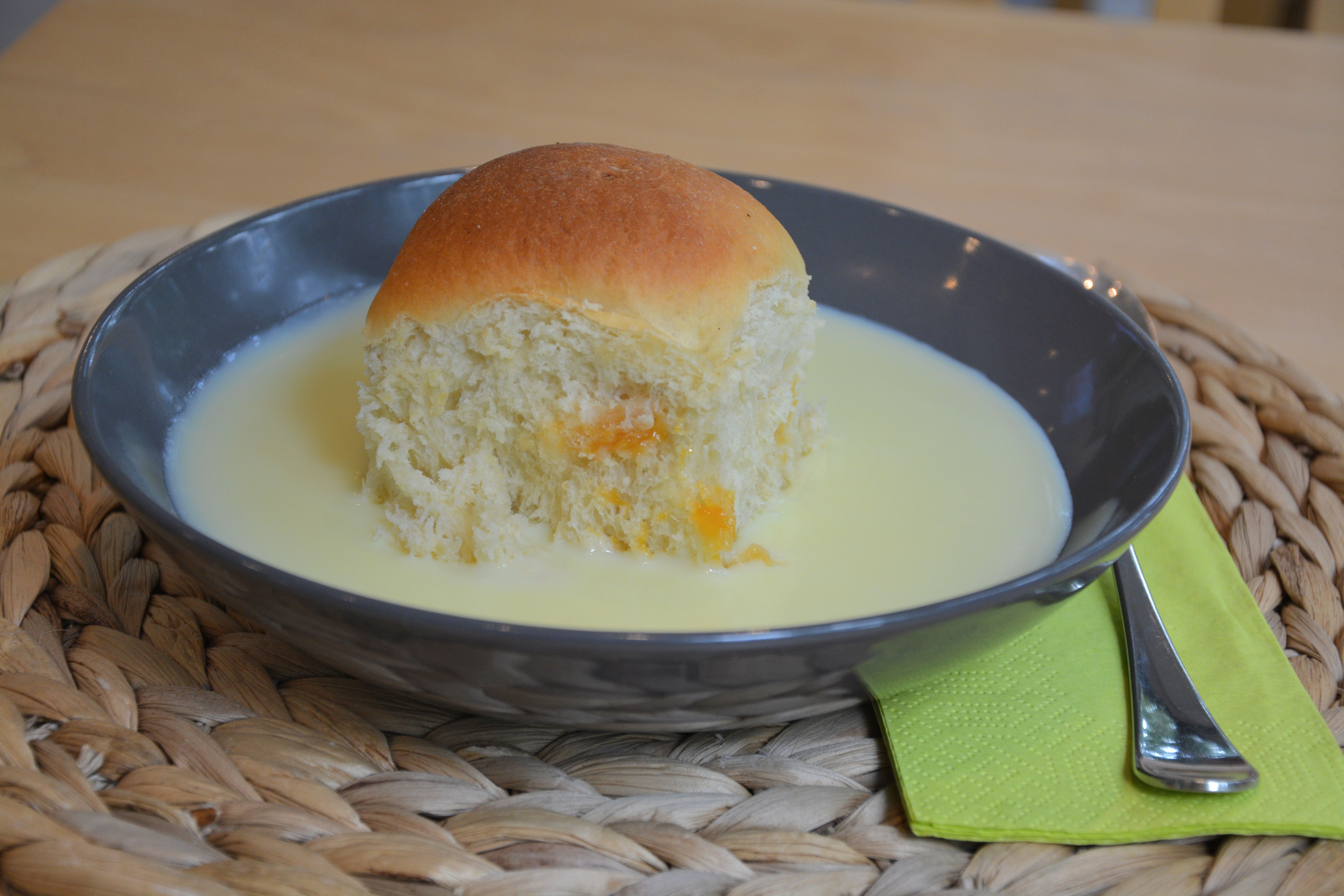 Čierny tanier s koláčom a vanilkovou omáčkou, vedľa neho zelený obrúsok s vidličkou.