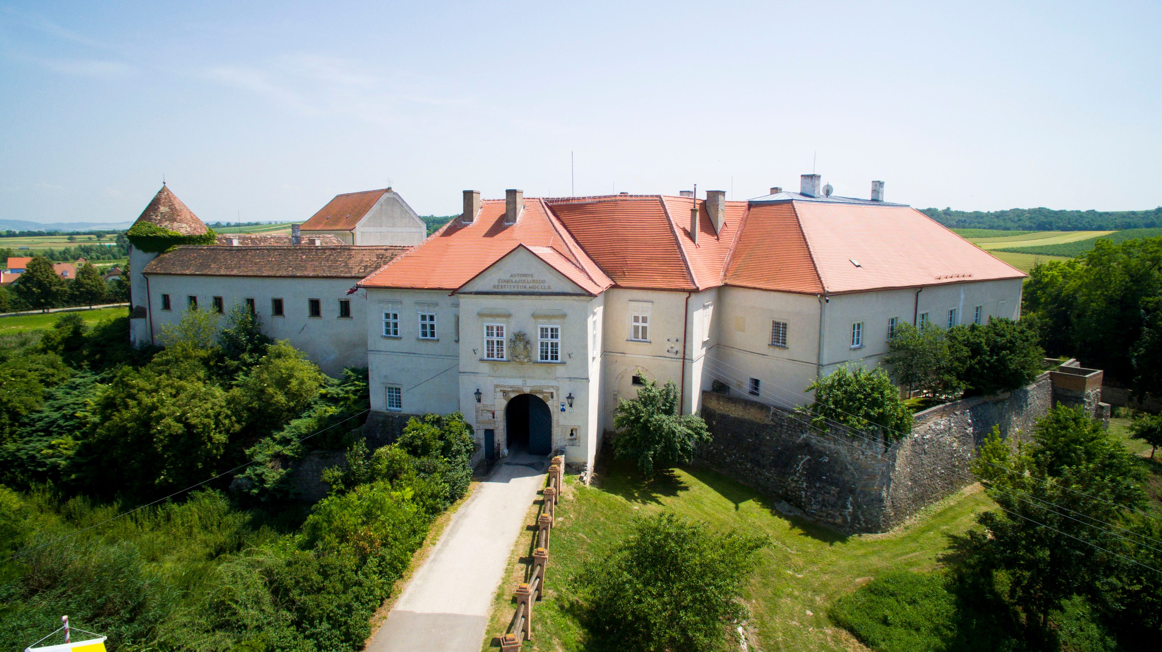 Letecký pohľad na hrad Mailberg s červenými strechami a okolitú krajinu.