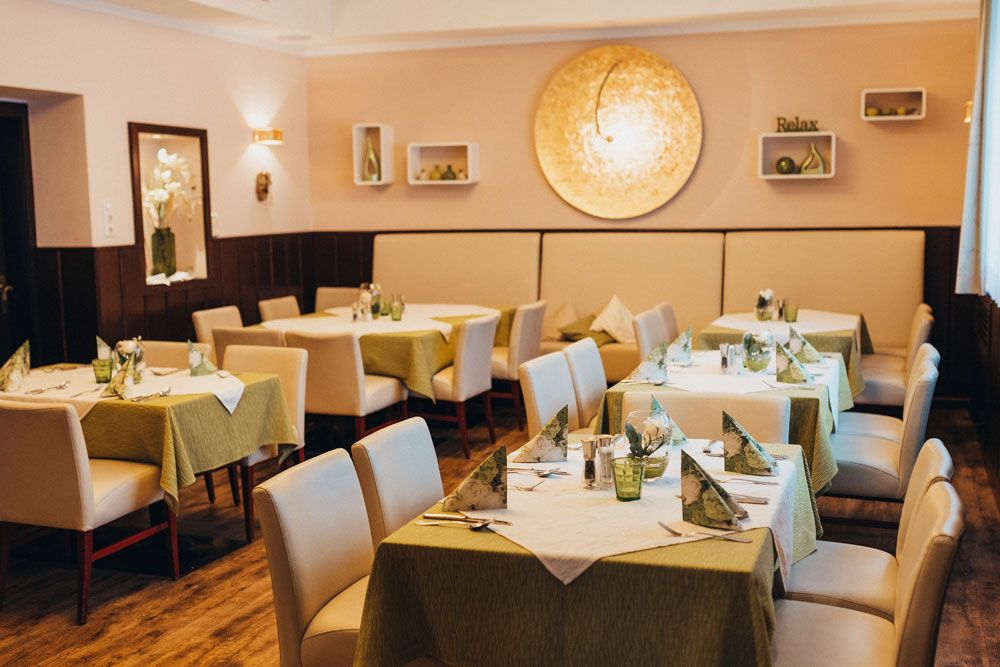 Elegantná reštaurácia s prestretými stolmi a zelenými obrusmi.