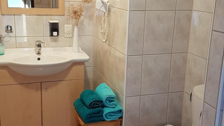 K&uacute;peľňa s um&yacute;vadlom, zrkadlom, toaletou a uter&aacute;kmi na stoličke.