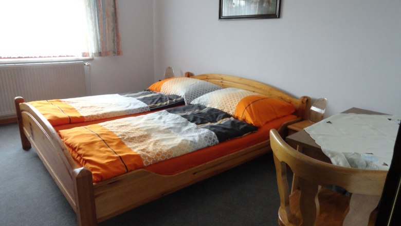 Jednoducho zariaden&aacute; sp&aacute;lňa s dvoma samostatn&yacute;mi l&ocirc;žkami, stolom a stoličkou.