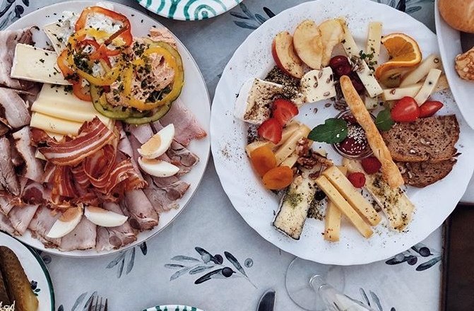 Dva taniere s &uacute;deninami, syrom, zeleninou a ovoc&iacute;m na stole.