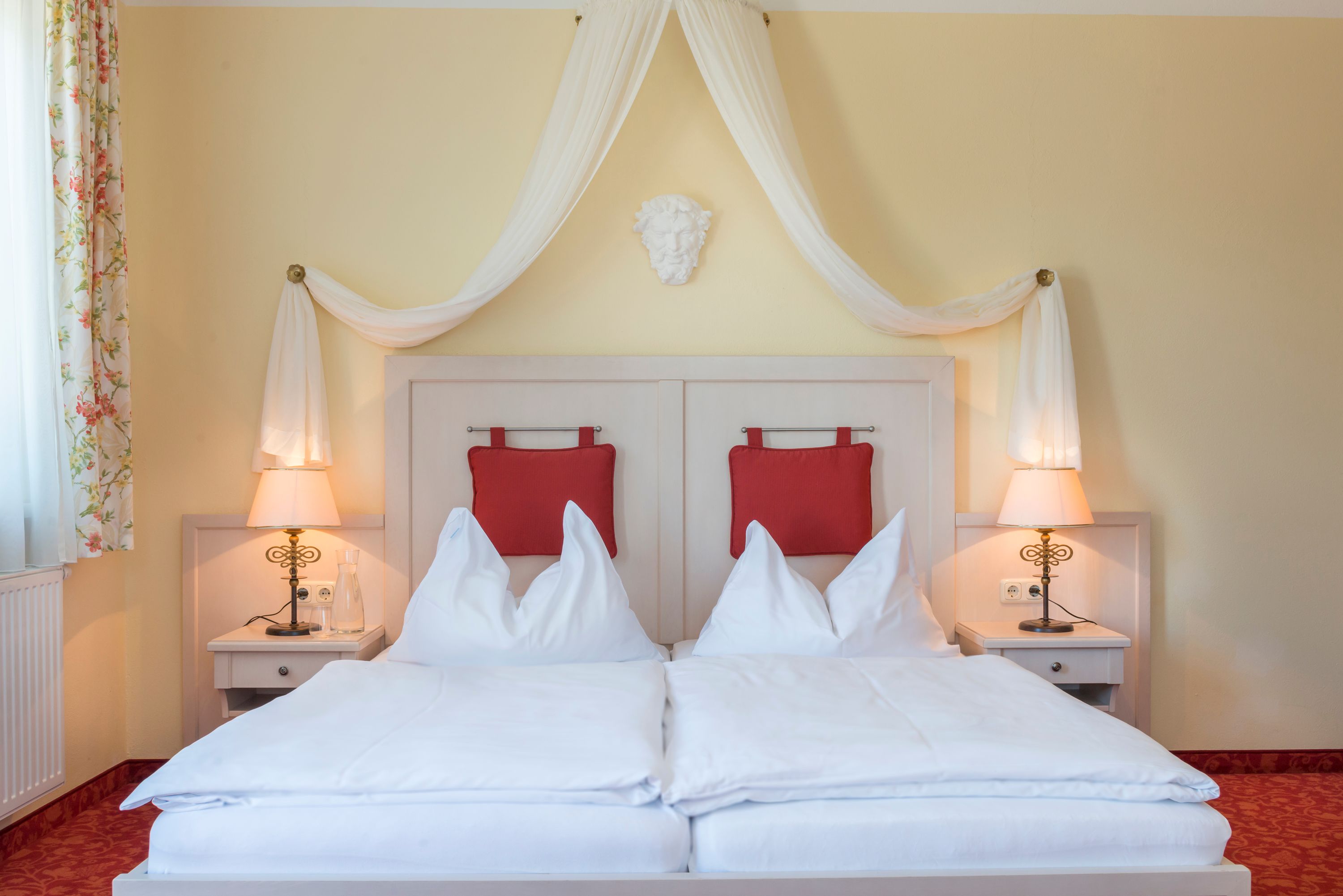 Pohľad na izbu s posteľou s baldachýnom a červeným čalúnením