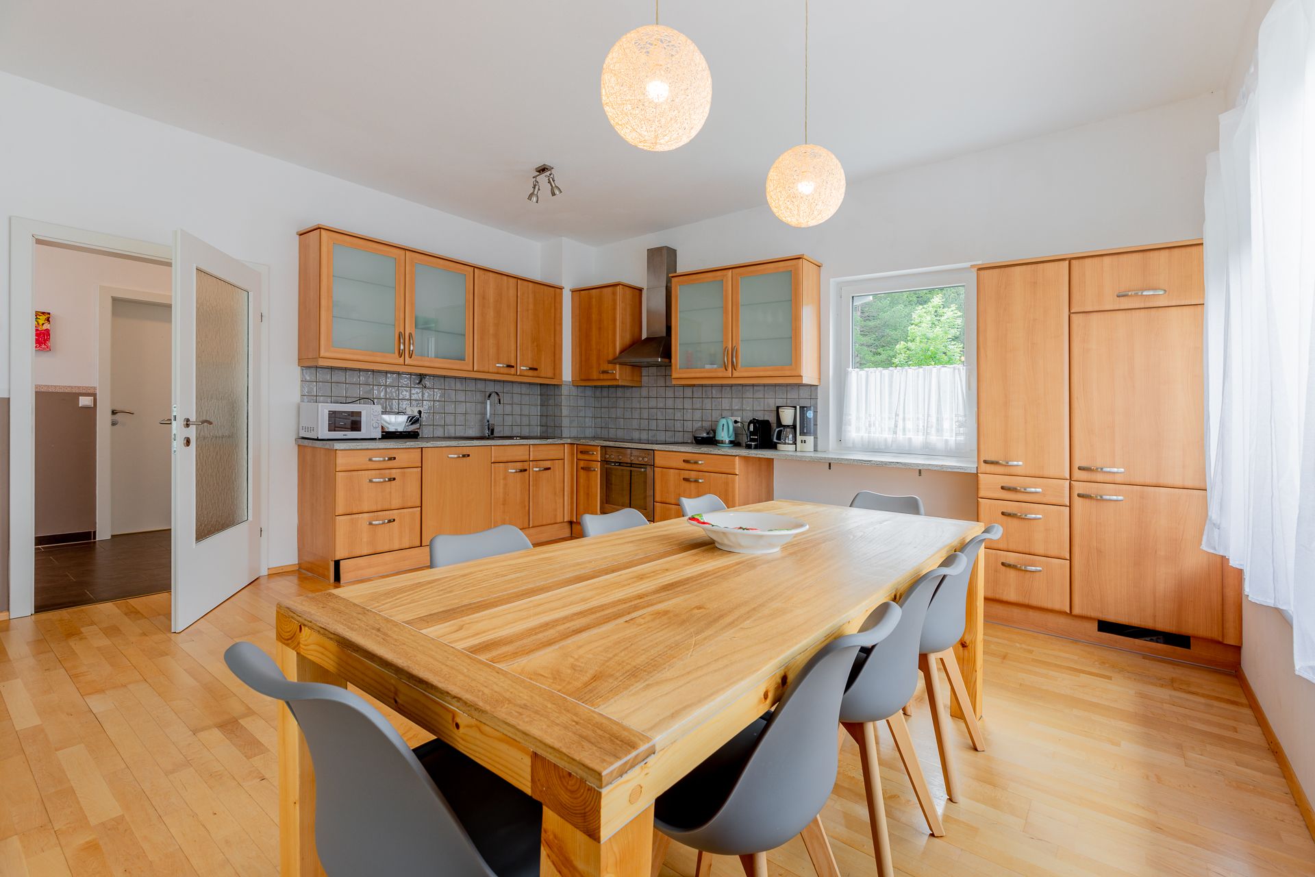 Moderná kuchyňa s dreveným nábytkom a veľkým jedálenským stolom.