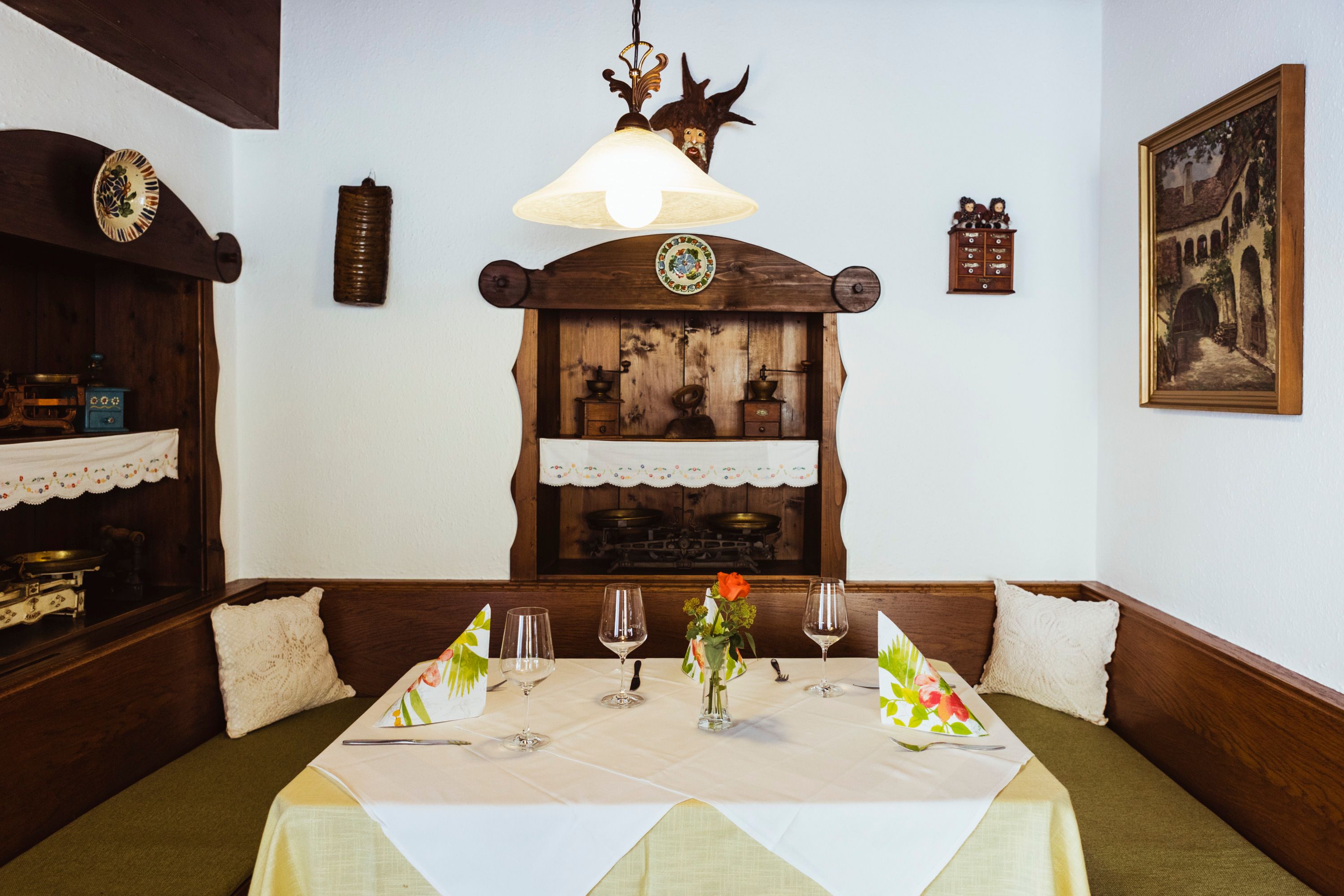 Útulné posedenie v reštaurácii s dreveným nábytkom, dekoratívnymi detailmi a prestretým stolom.