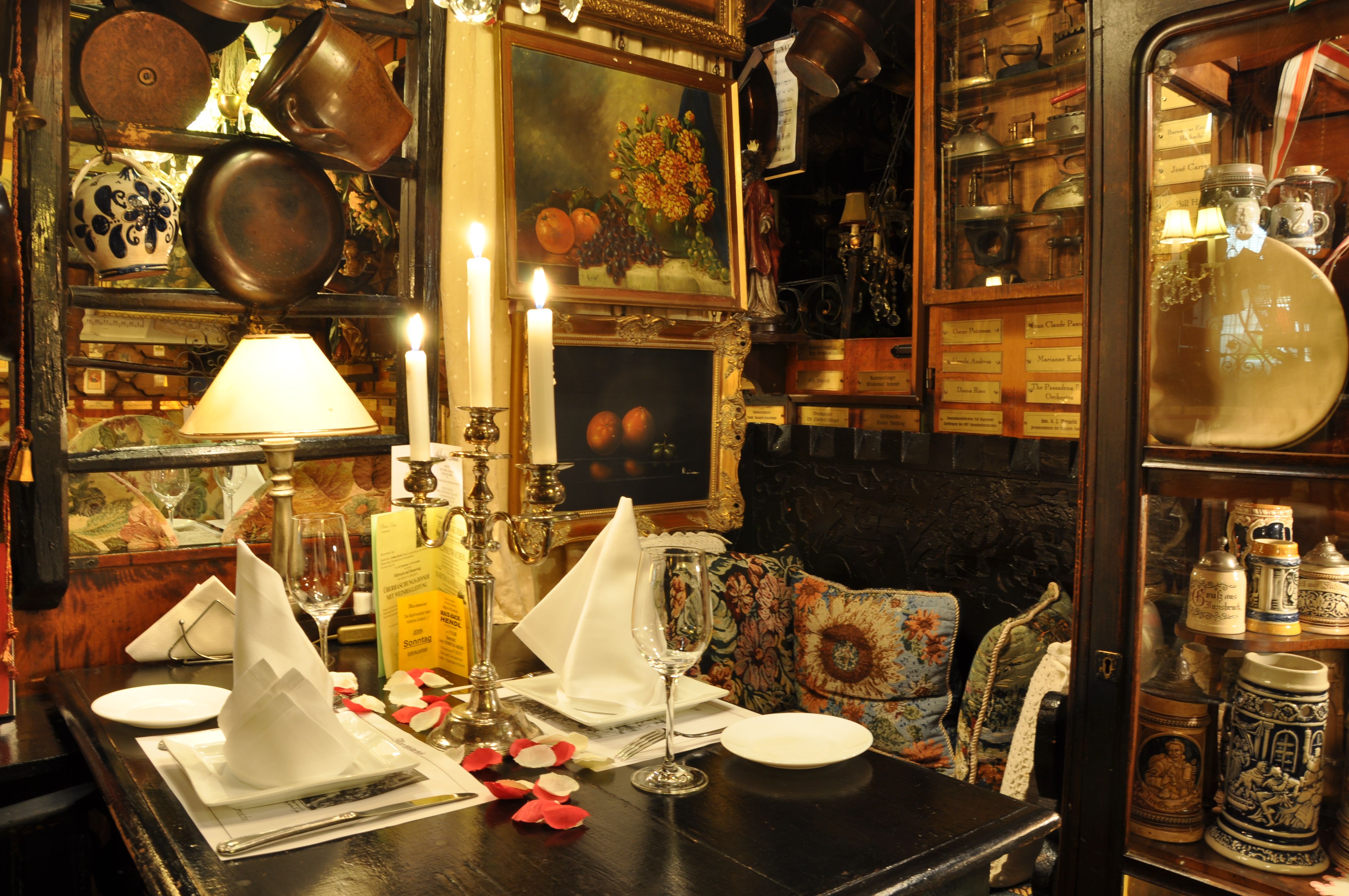 Útulne prestretý stôl v rustikálnej reštaurácii so svietnikmi, obrazmi a starožitnými predmetmi.