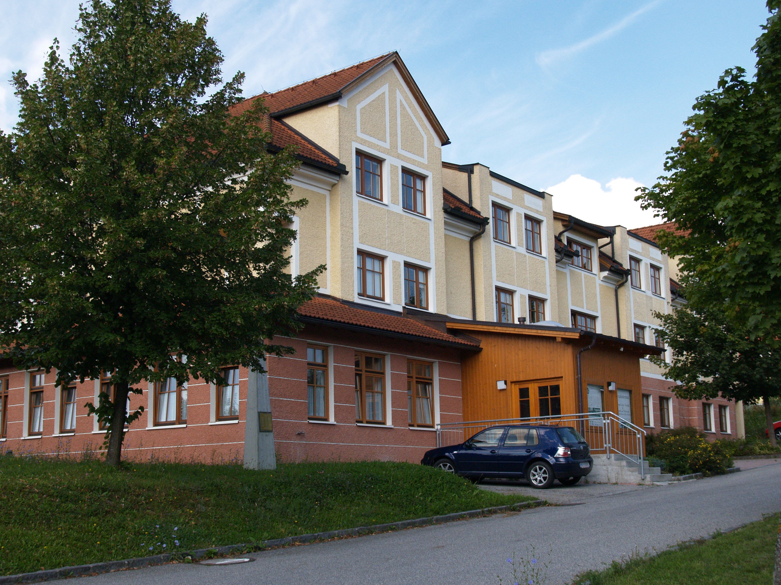 Dom pre hostí HLUW-Yspertal so zaparkovaným autom a stromami.