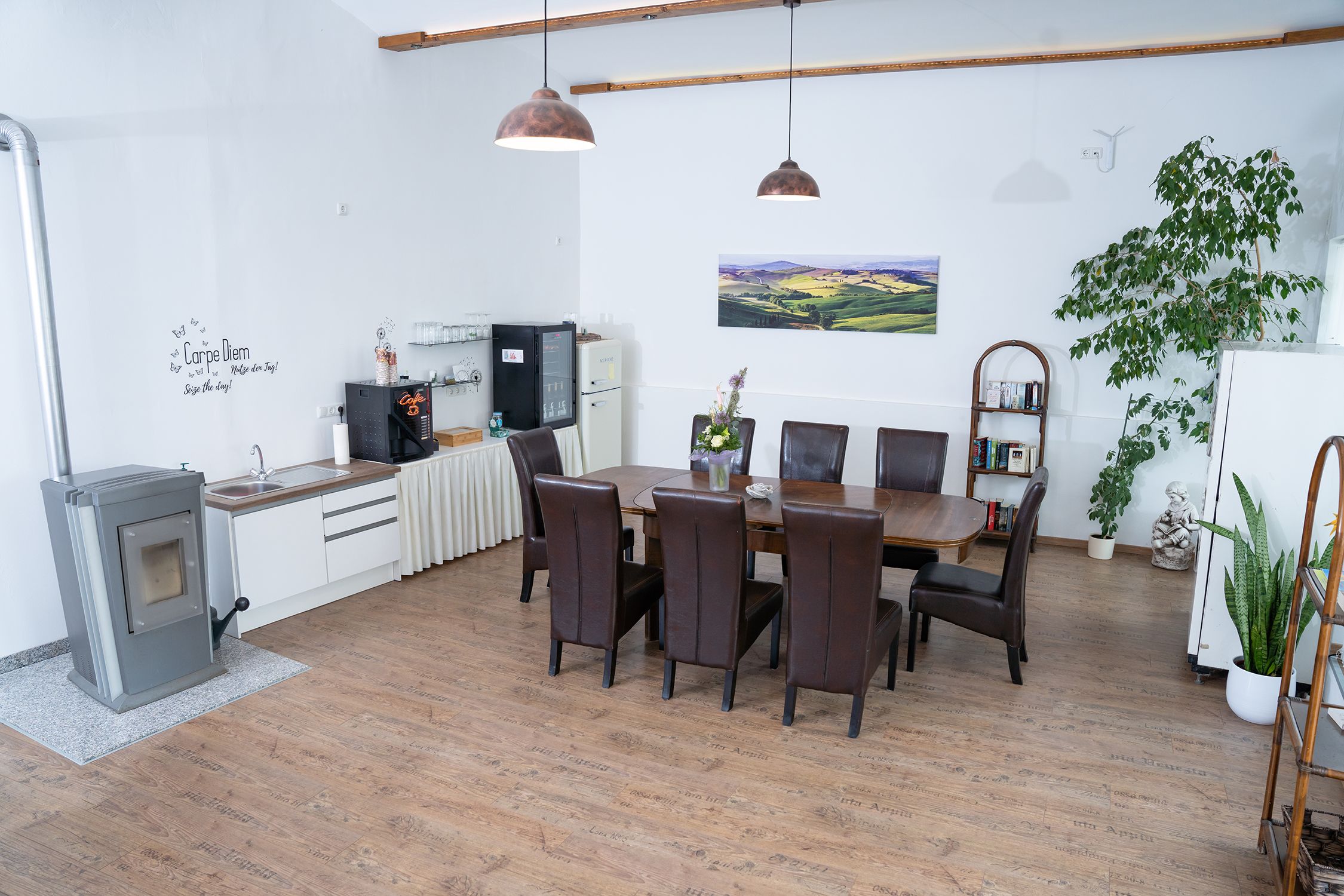 Útulná izba s jedálenským stolom, stoličkami, rastlinami a kuchynským kútom.