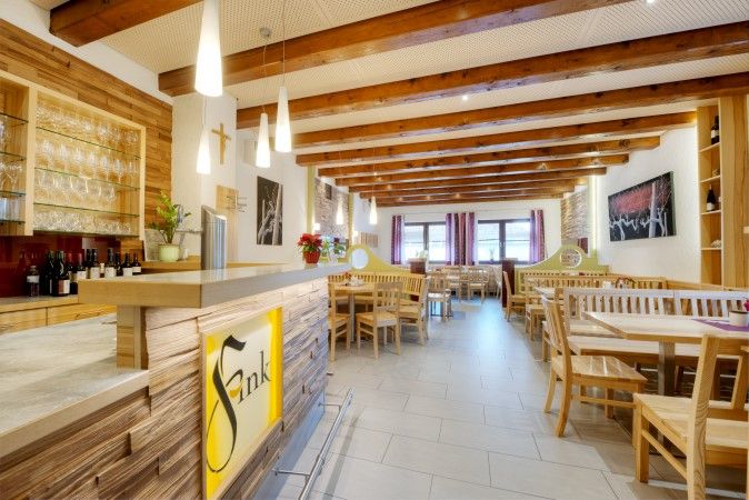 Pohľad do interiéru útulnej jedálne s dreveným nábytkom a barom v štýle vinárne.