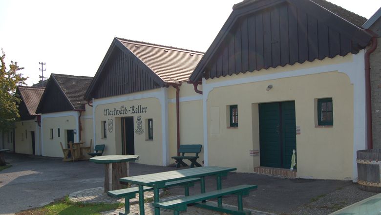 Tradičné vínne pivnice s drevenými lavicami a vonkajšími stolmi.