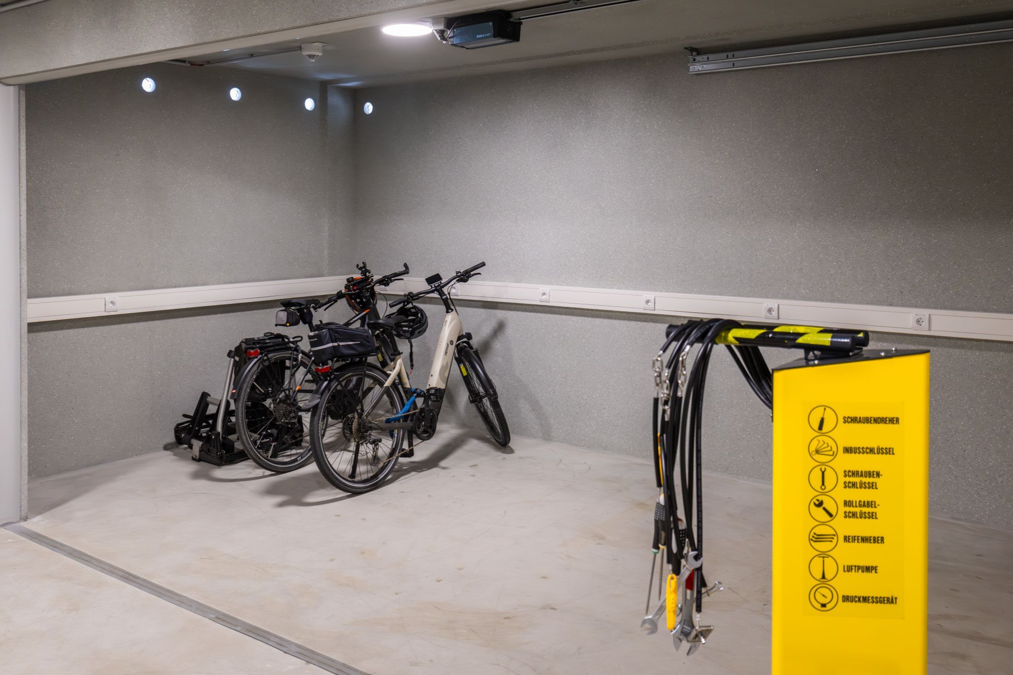 Úschovňa bicyklov s dvoma bicyklami a žltou stanicou na náradie.