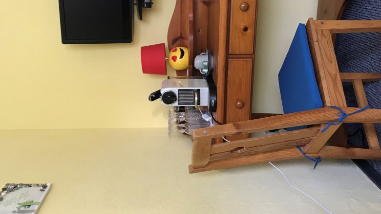 Mal&yacute; dreven&yacute; stol&iacute;k s k&aacute;vovarom, poh&aacute;re, lampa a telev&iacute;zor na stene.