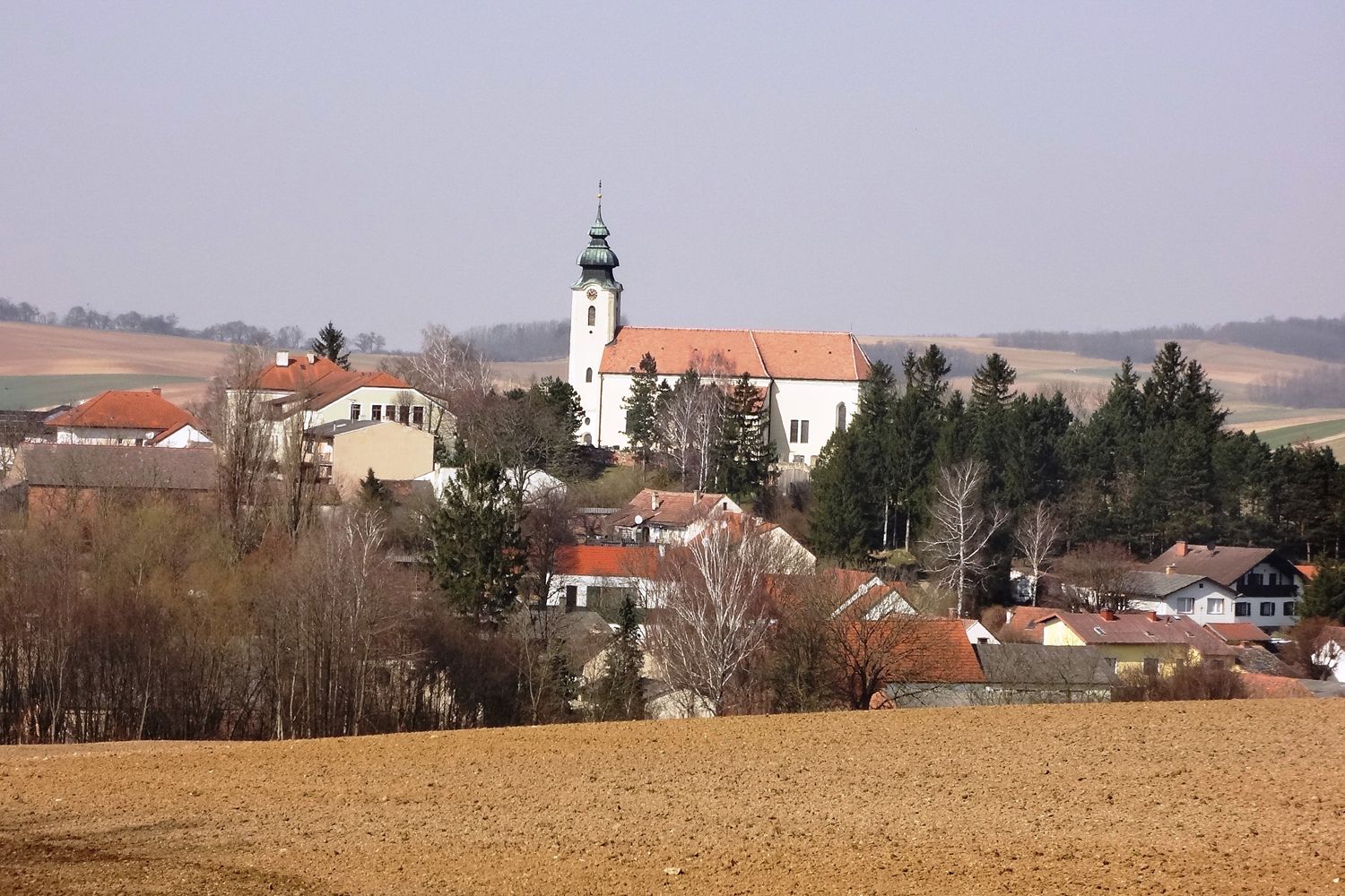 Pohľad na obec Gnadendorf s kostolom a okolitými domami vo vidieckej krajine.