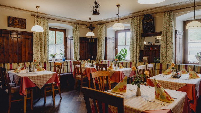 Útulný hostinec s dreveným nábytkom a károvanými obrusmi.