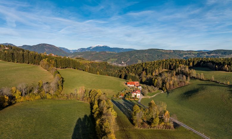 Krajina pri St. Corona am Wechsel so zelenými kopcami a farmou.