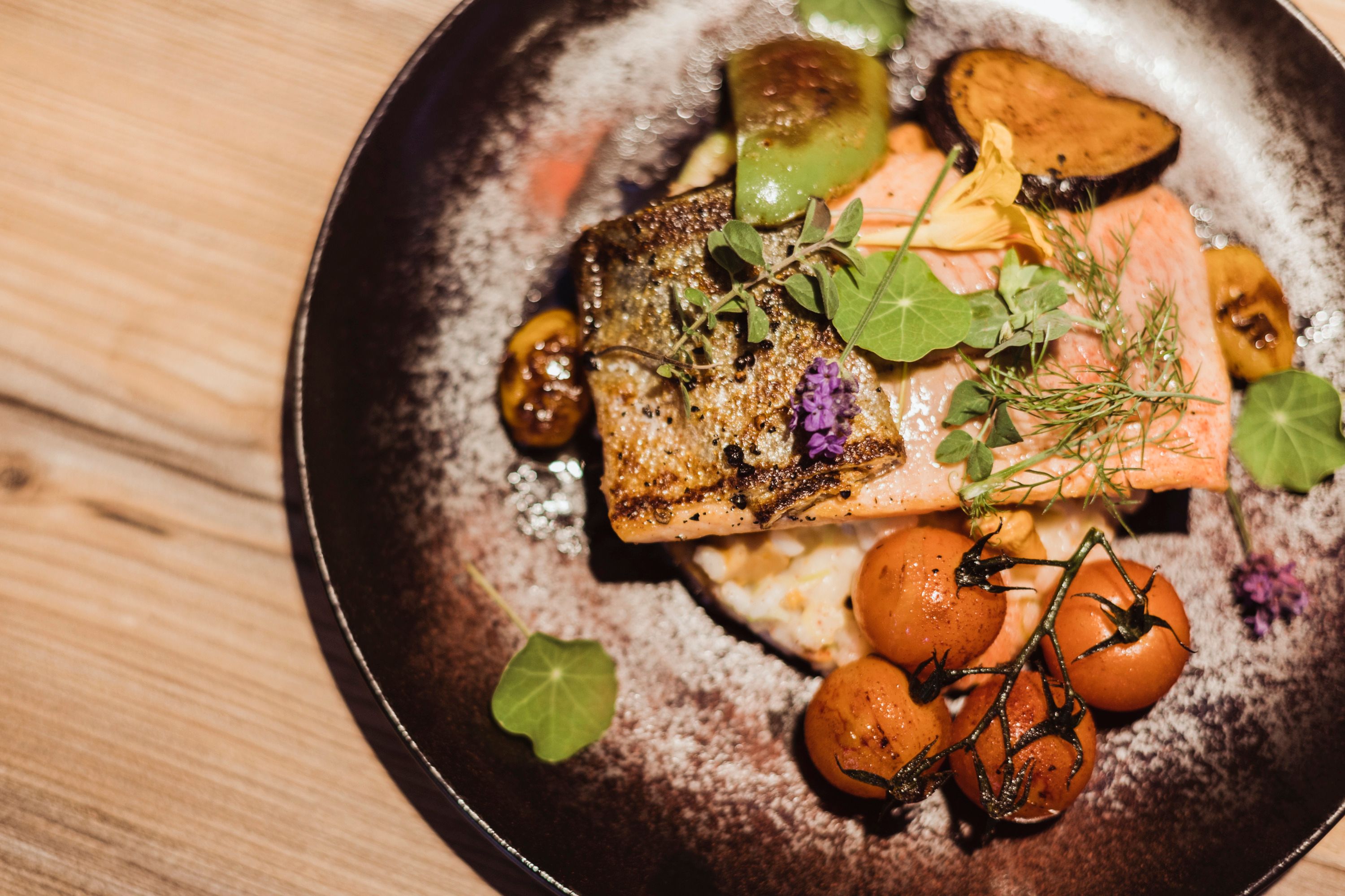 Filet z lososa na tanieri s rizotom z grammelov so zeleninou a bylinkami.