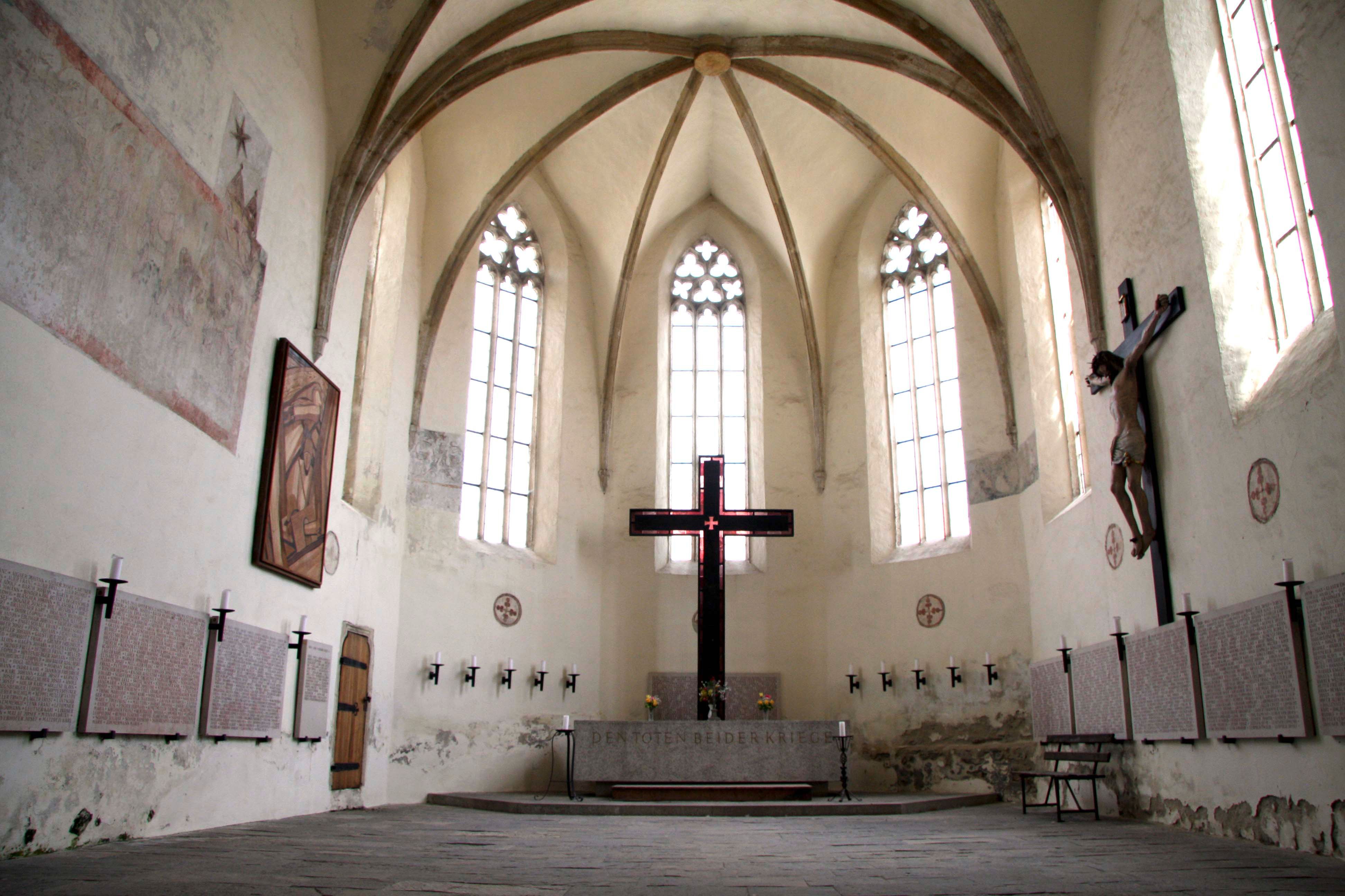 Pohľad do interiéru kostola Frauenbergkirche Stein s gotickými oknami a veľkým krížom.