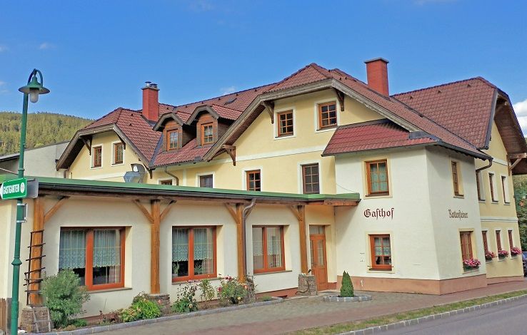Tradičný hostinec so žltou fasádou a červenými strechami.