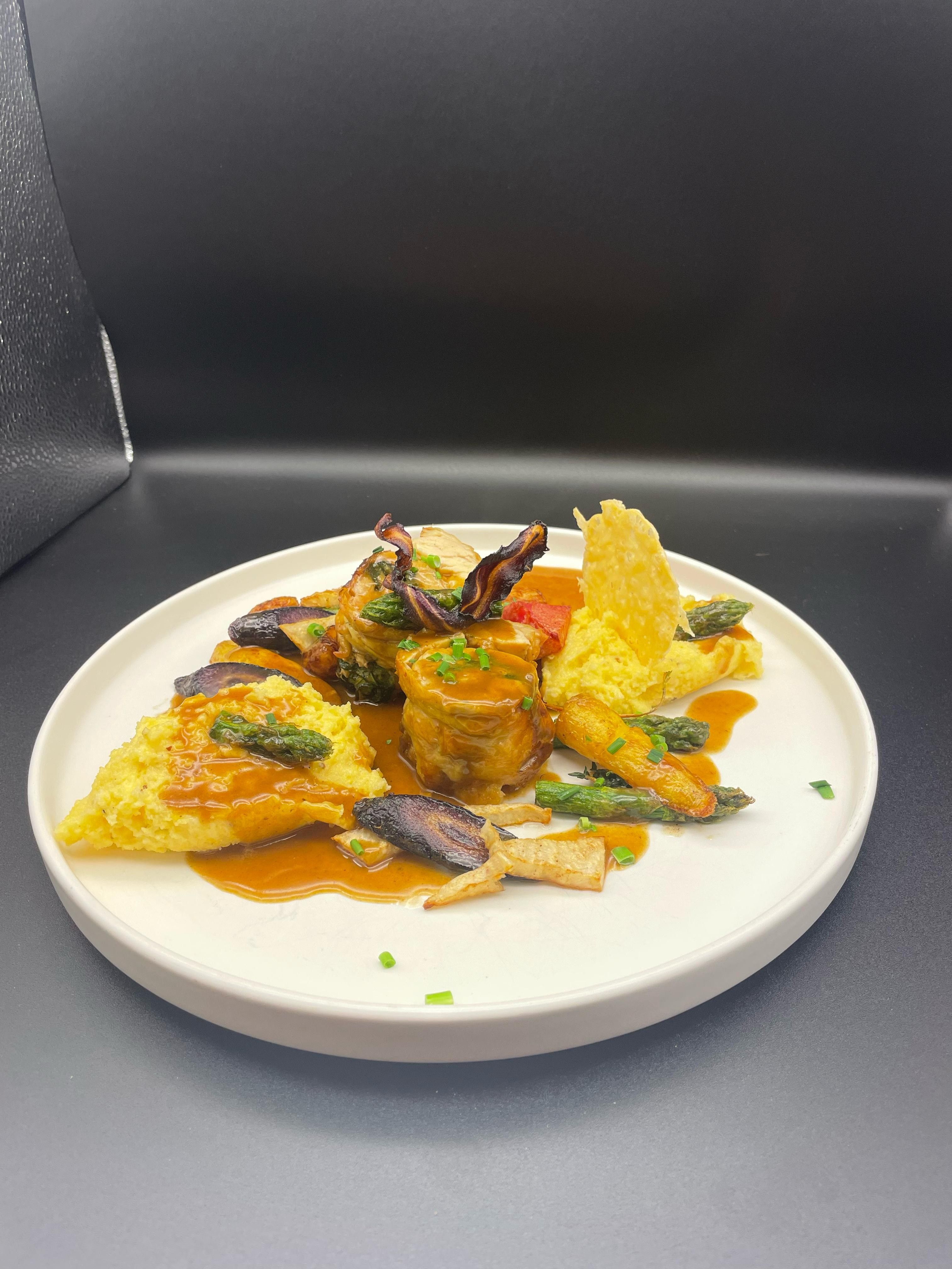 Gurmánske jedlo na bielom tanieri s mäsom, zeleninou a omáčkou.