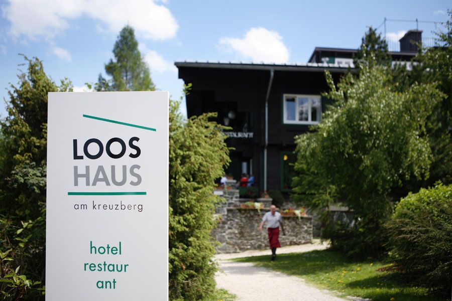 Vchod do Looshaus am Kreuzberg s nápisom a záhradou.