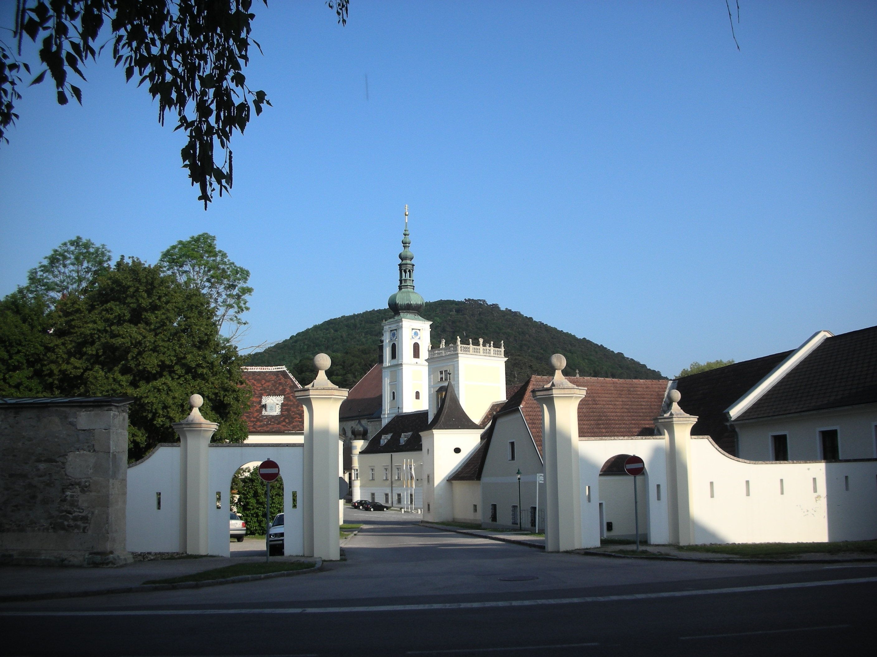 Vstupná brána opátstva Heiligenkreuz s kostolnou vežou v pozadí.