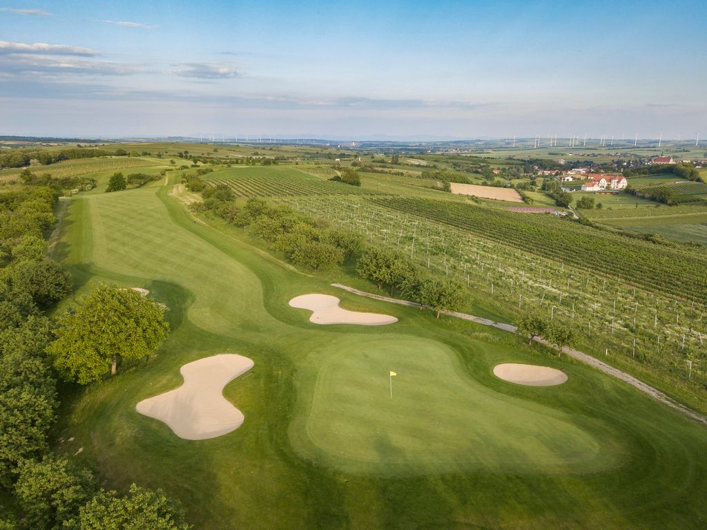 Letecký pohľad na golfové ihrisko s pieskovými bunkrami a okolitými vinicami.