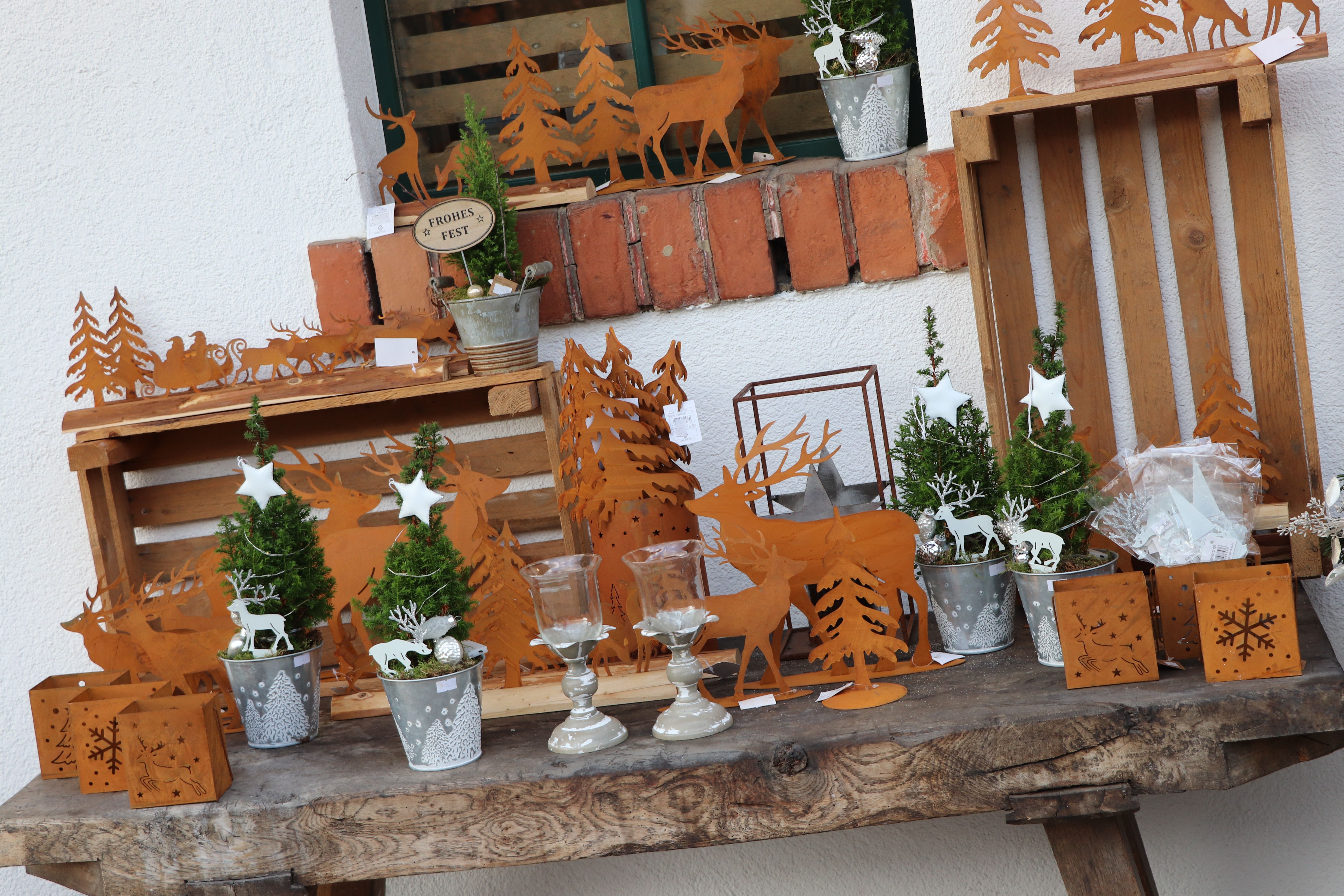 Vianočná dekorácia s kovovými motívmi sobov a vianočného stromčeka na drevenom stole.