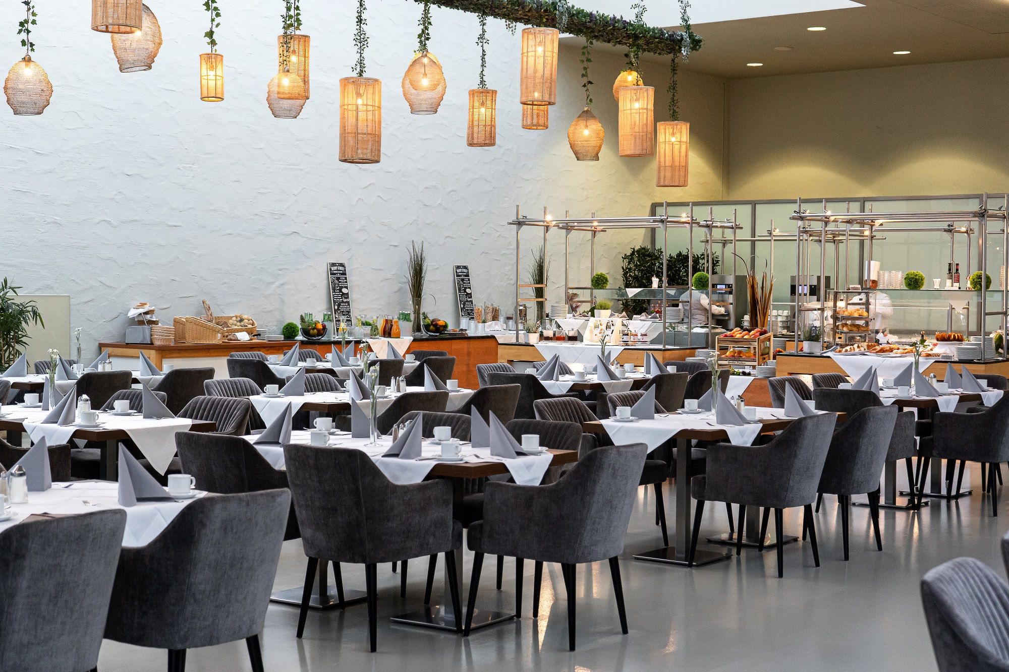 Pohľad do interiéru štýlovej reštaurácie s položenými stolmi a závesnými lampami.