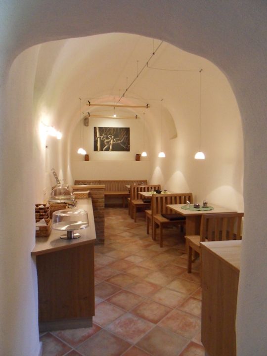 Útulná raňajková miestnosť s dreveným nábytkom a klenutým stropom.