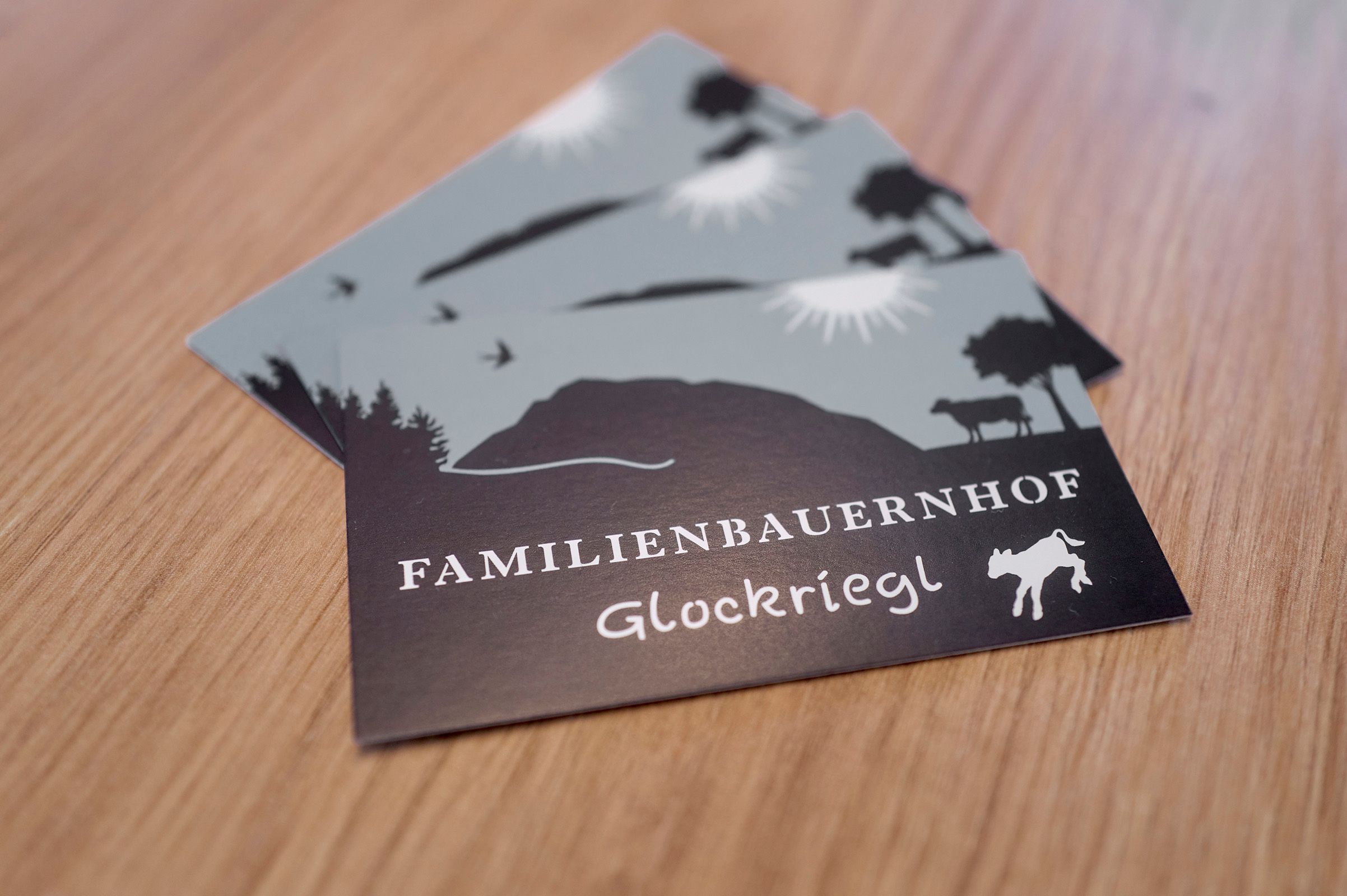 Pohľadnice s logom rodinnej farmy Glockriegl na drevenom stole.