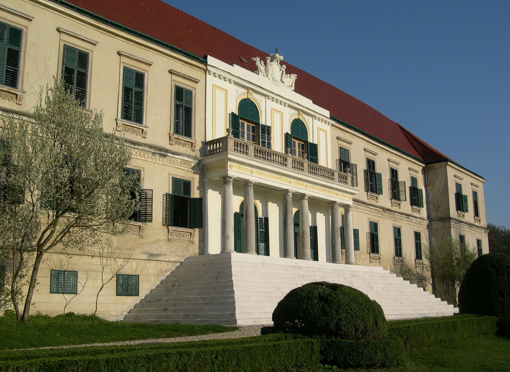 Zámok Loosdorf so širokým schodiskom a zelenými okenicami.
