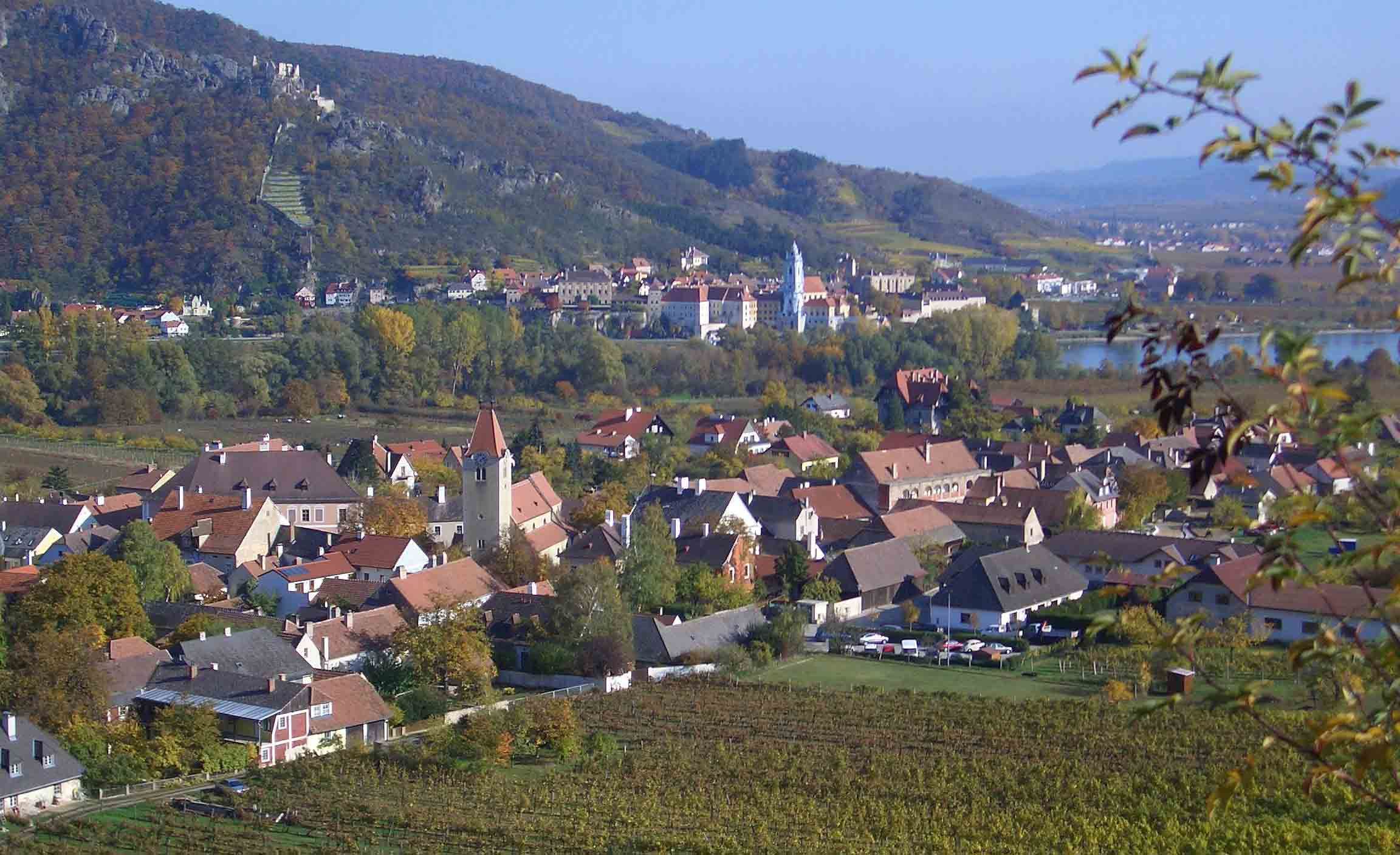 Panoráma malebného mesta s vinicami a riekou v pozadí.