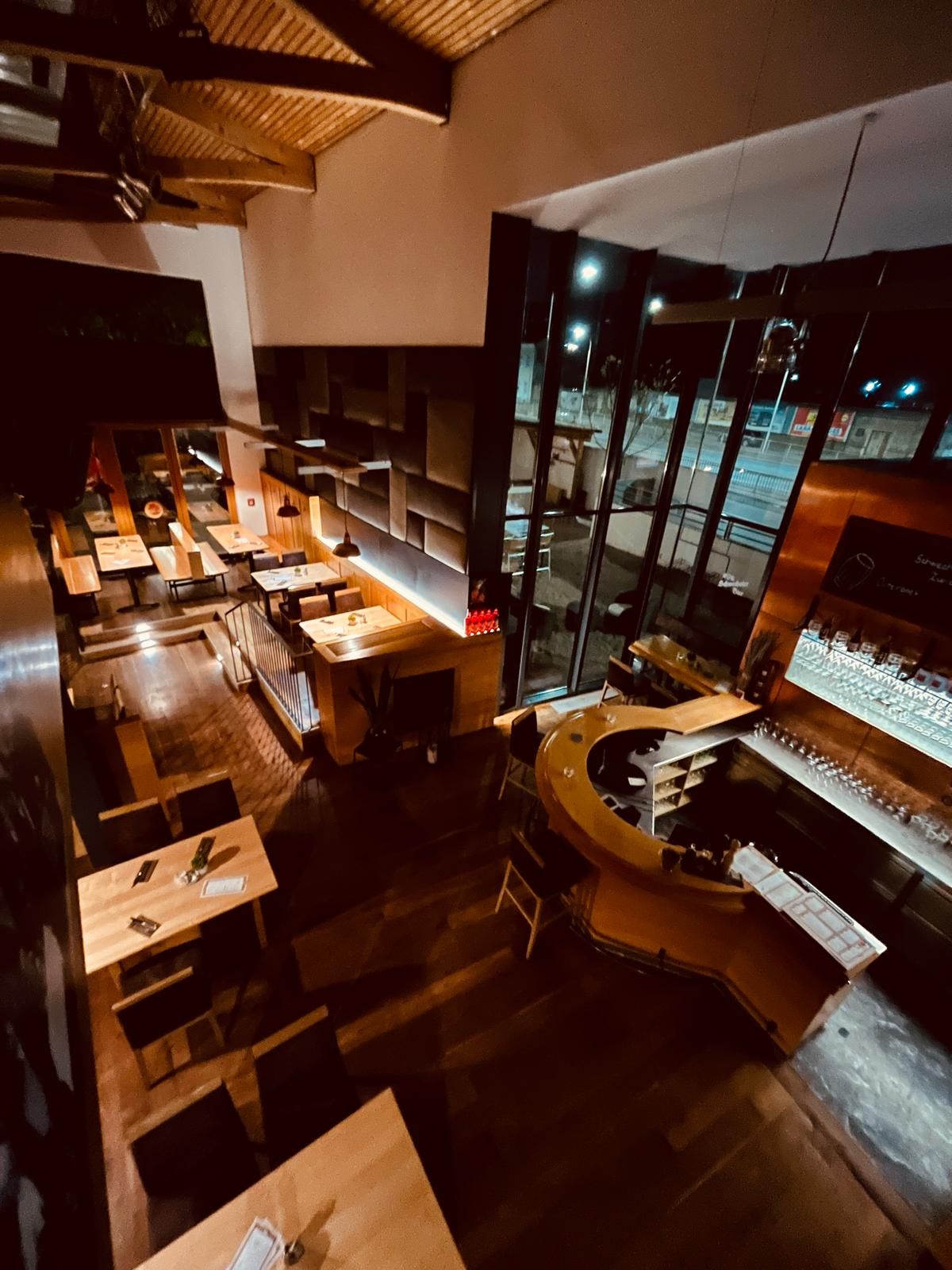 Pohľad na interiér Brauhaus Schwechat v noci s drevenými stolmi a barom.