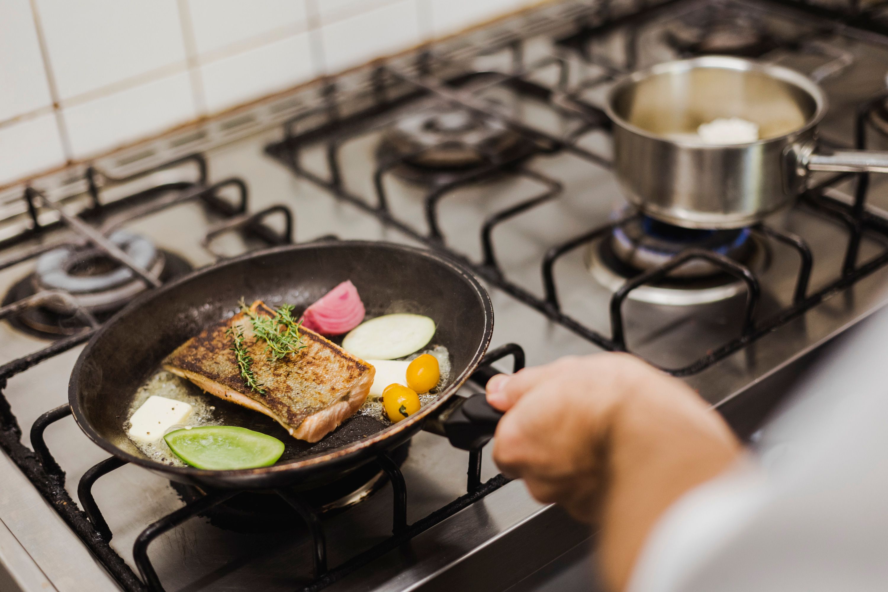 Panvica s rybou, zeleninou a bylinkami na varnej doske.