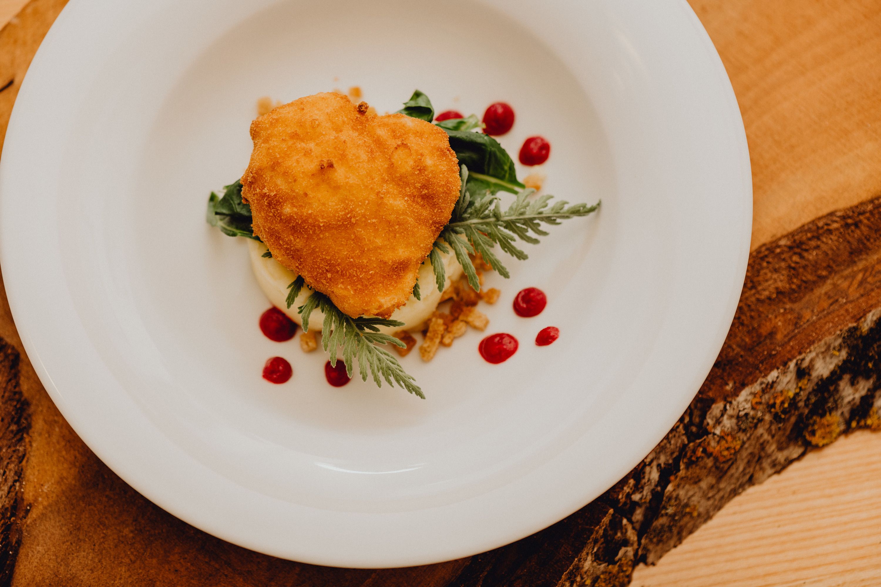 Pečené vajce na tanieri s pyré a červenými bodkami.