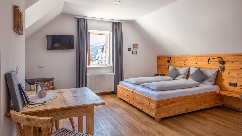 Bytový dom Leopold an der Ybbs, © Niederösterreich Werbung / Maximilian Pawlikowsky Útulná spálňa s dreveným nábytkom a šikmým stropom.