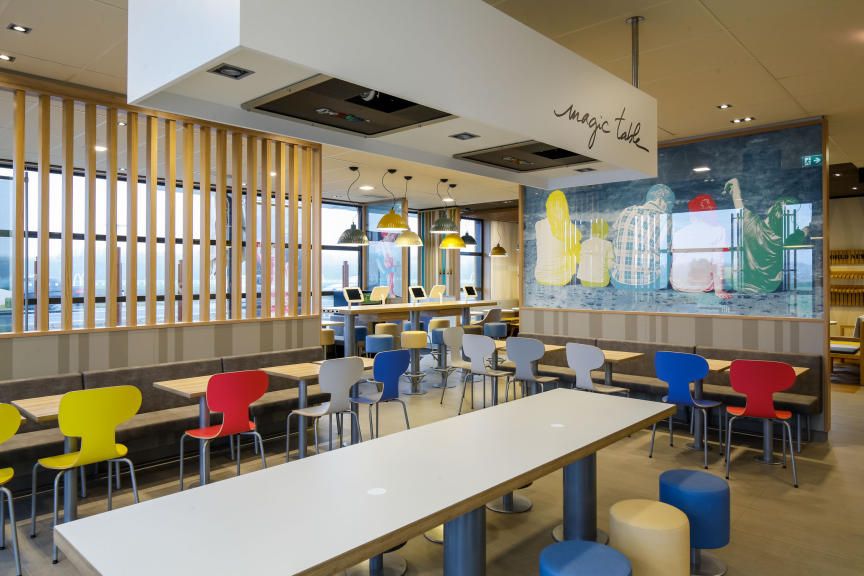 Pohľad do interiéru modernej reštaurácie McDonald's s farebnými stoličkami a stolmi.