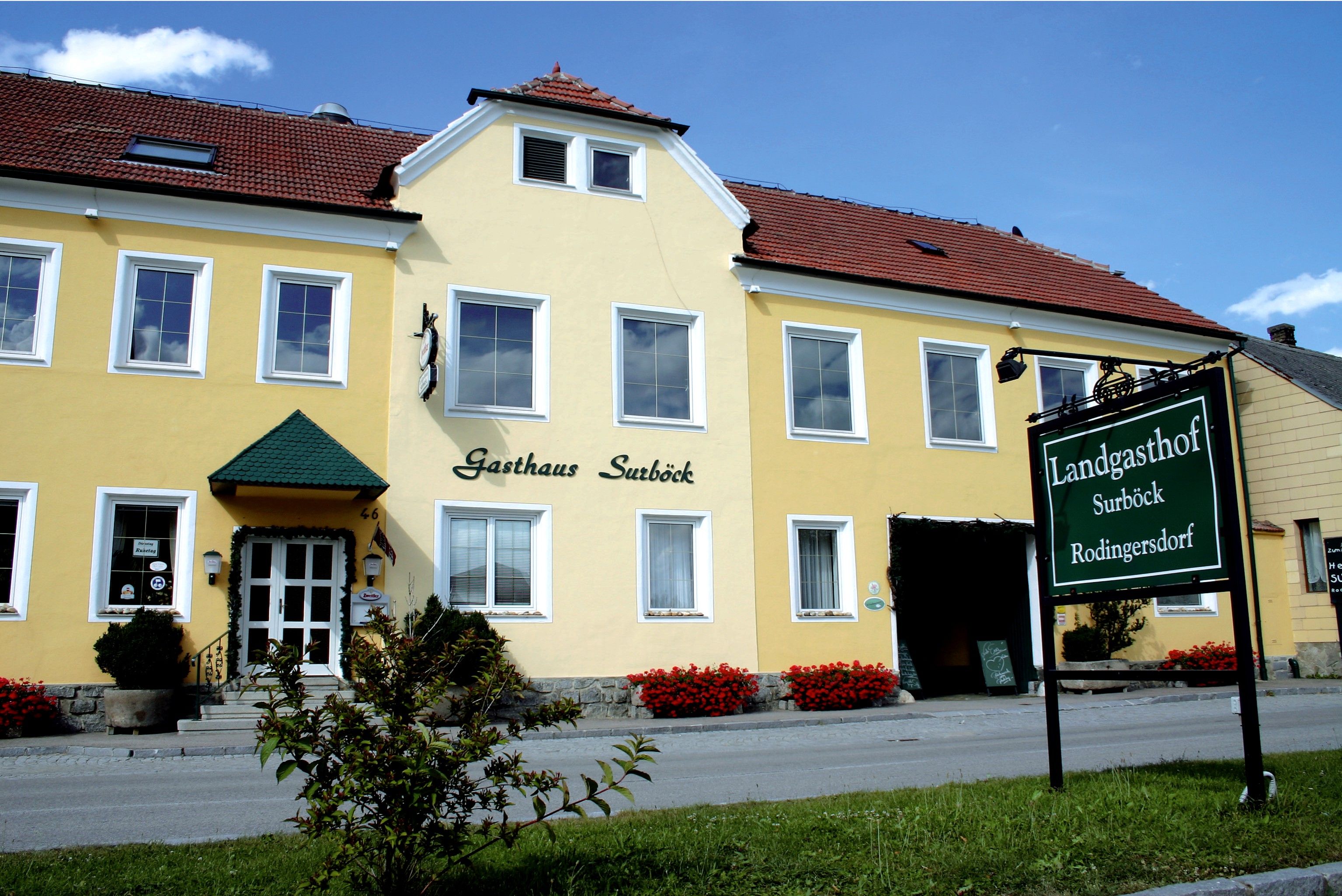 Žltá budova s nápisom "Gasthaus Surböck" a zeleným nápisom "Landgasthof Surböck Rodingersdorf".