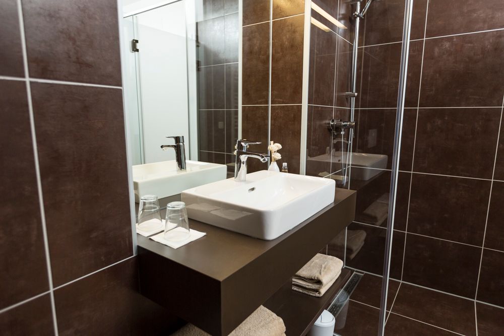 Moderná kúpeľňa s umývadlom, zrkadlom a sprchovacím kútom.