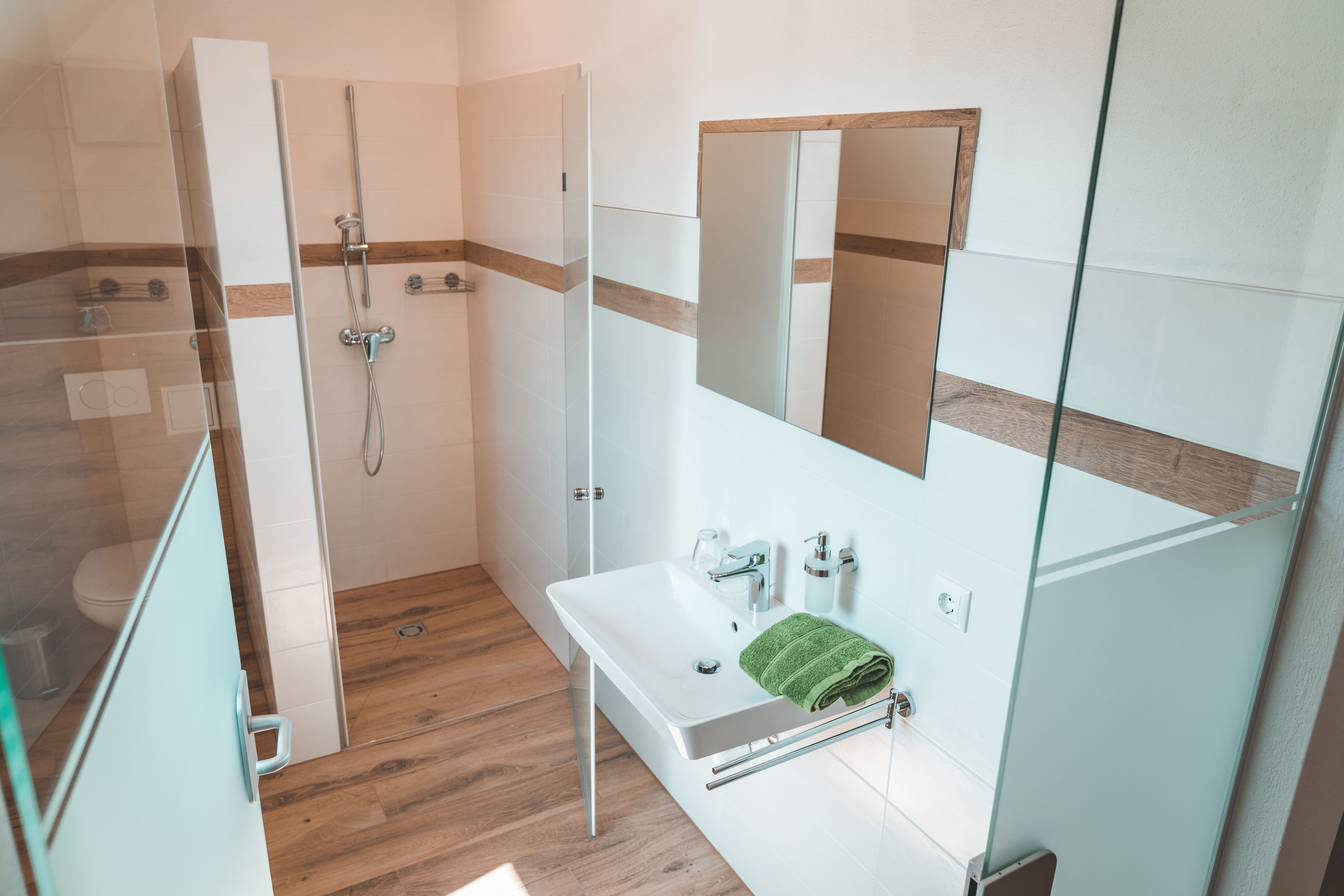 Moderná kúpeľňa so sprchovacím kútom, umývadlom a zrkadlom.