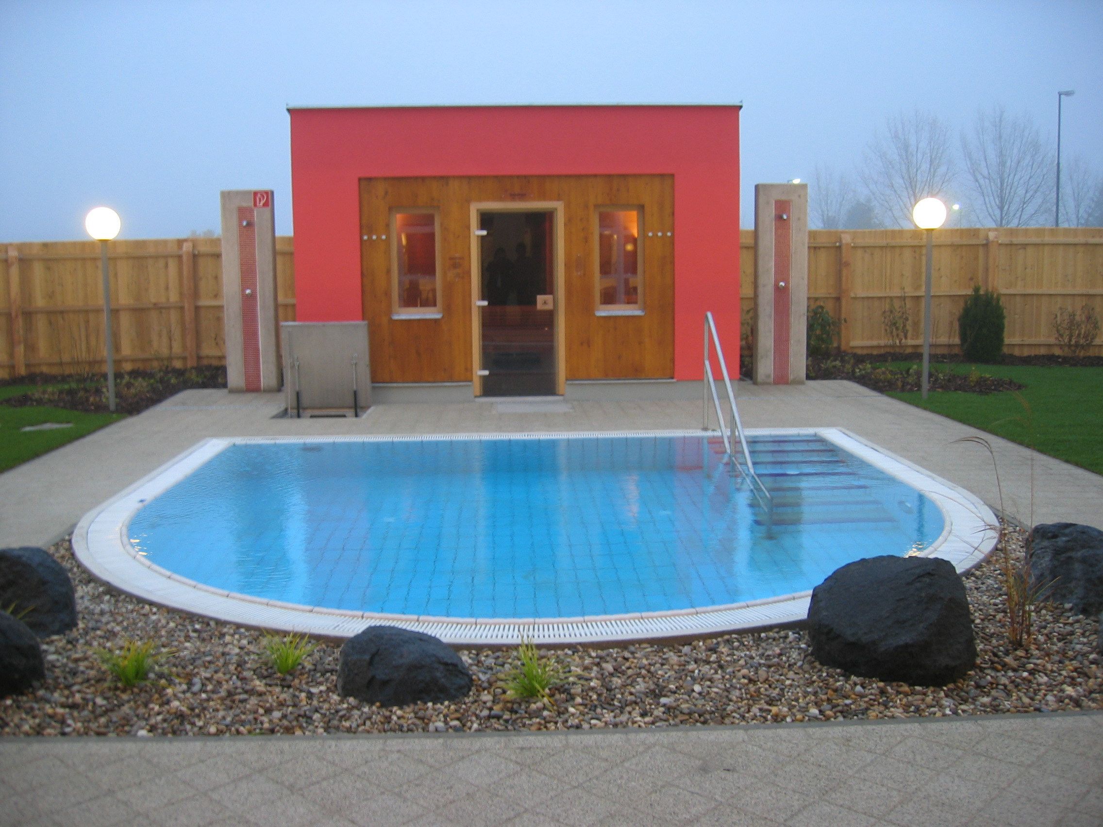 Pohľad zvonku na saunu s malým bazénom a záhradou.